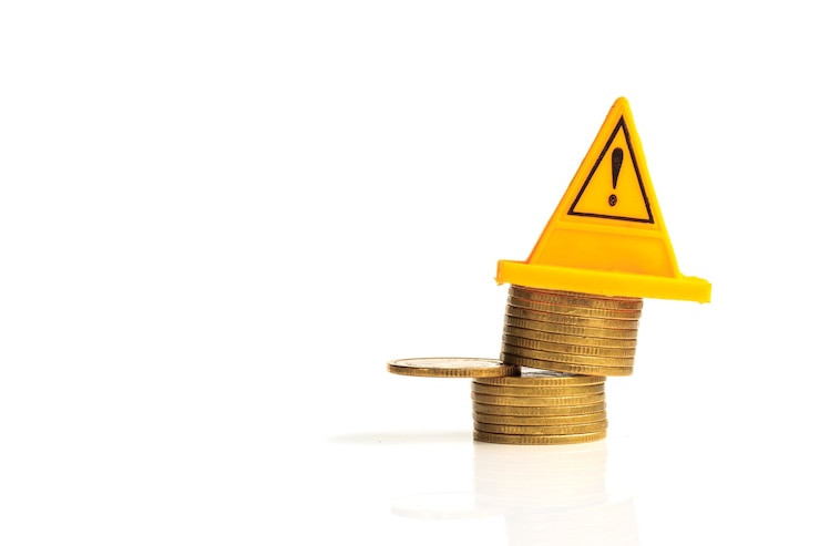 Foto riesgo financiero. monedas cayendo y etiqueta de advertencia en whitebackground
