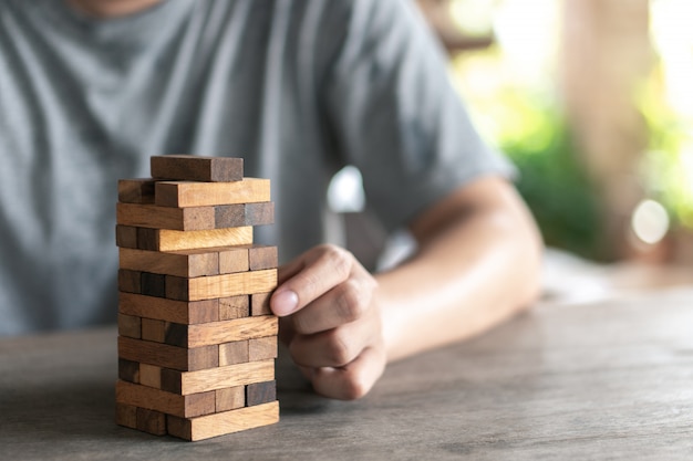 El riesgo ocurrirá. La mano del ingeniero juega un juego de bloques de madera sobre madera.