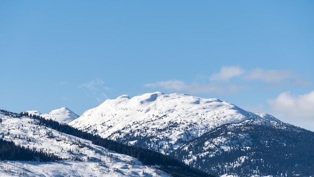 Riesige Berge, die von Schnee und sonnigem Himmel mit Wolken bedeckt sind, British Columbia, Kanada