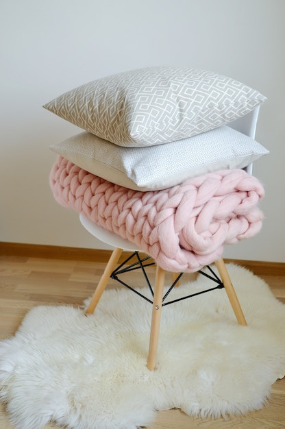Riesige rosa Plaid-Decke Woolen gestrickt auf weißer hölzerner Schemel-Stuhl-Ausgangsskandinavier-Art