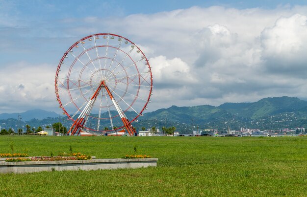 Riesiges rotes und weißes Riesenrad mit Bergen