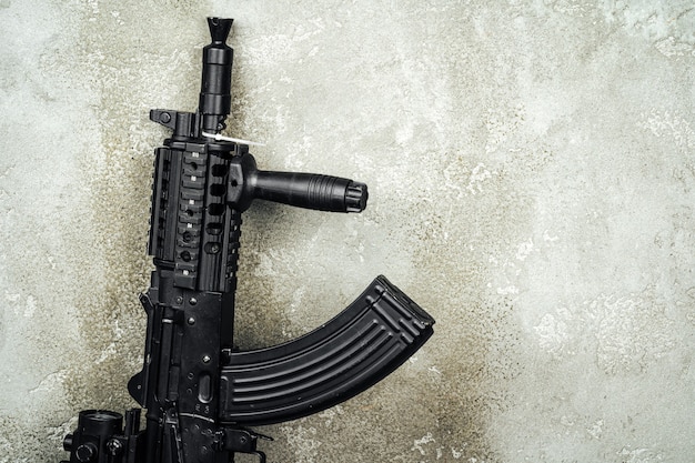 Foto rifle ak-47 contra parede de concreto