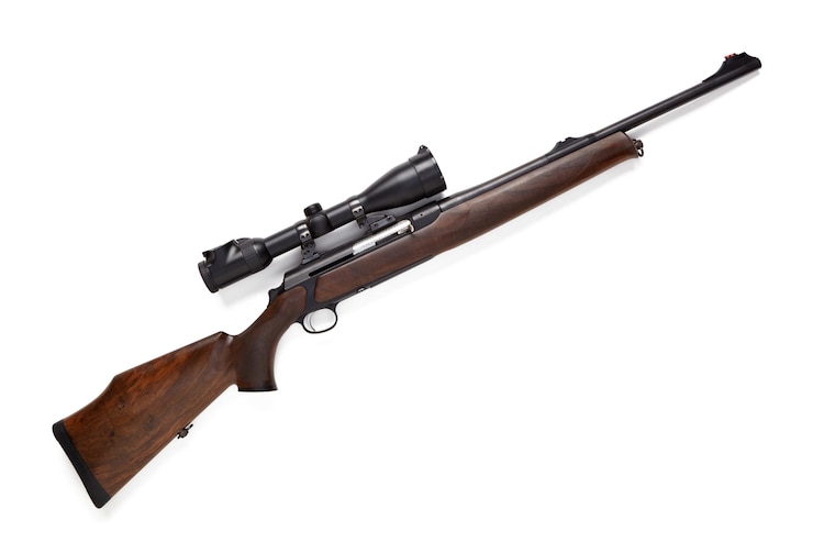 Foto rifle de caza con mira óptica aislado sobre fondo blanco.