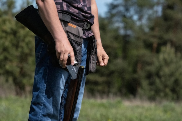 Foto rifle de caça disparando caça na floresta caçador carregando arma com balas um rifle em uma mão de homem fechada