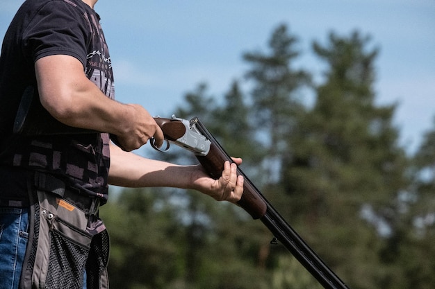 Foto rifle de caça disparando caça na floresta caçador carregando arma com balas um rifle em uma mão de homem fechada