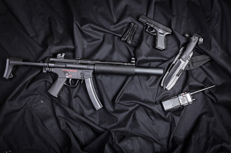 Foto rifle, pistola, cuchillo con funda, brújula y cuaderno con bolígrafo sobre tela negra