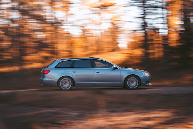 Riga, Letonia, 21 de octubre de 2021: Rápido Audi A6 3.0 TDI Quattro en el soleado bosque otoñal, automático en cámara rápida con un fondo otoñal borroso.