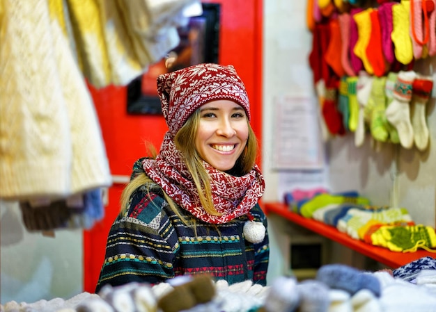 Riga, Letônia - 24 de dezembro de 2015: Sorrindo jovem retratado em uma das barracas durante o mercado de Natal de Riga. O mercado ocorreu do final de novembro até o início de janeiro.