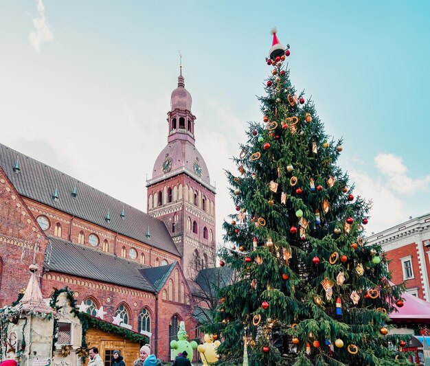 Riga, Letônia - 25 de dezembro de 2015: Mercado de pessoas e Natal na Praça Dome com árvore de Natal e barracas em Riga na Letônia no inverno.