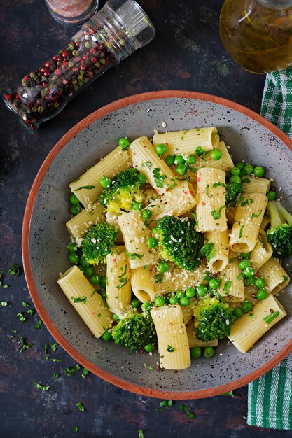 Foto rigatoni de massa com brócolis e ervilhas verdes. menu vegano. comida dietética. postura plana. vista do topo.