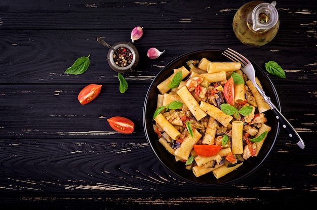 Rigatoni pasta con carne de pollo, berenjenas en salsa de tomate en un tazón. Cocina italiana. Vista superior. Copia espacio