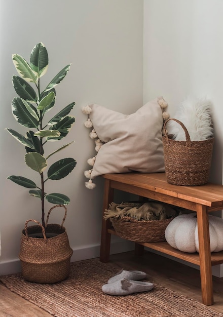 Un rincón acogedor de la sala de estar un banco de madera con una almohada y una manta cestas unas zapatillas de flores de ficus en una alfombra de yute una casa acogedora