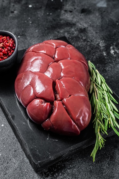 Rind Kalb Niere rohes Innereien Fleisch auf Marmorplatte mit Rosmarin Schwarzer Hintergrund Ansicht von oben