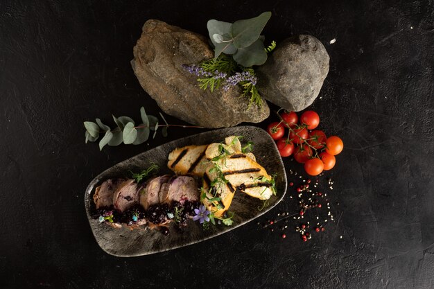 Rinderbrötchen mit Beerenmarmelade und gegrilltem Ciabatta, dekoriert mit frischen Blumen und Sprossen junger Erbsen.