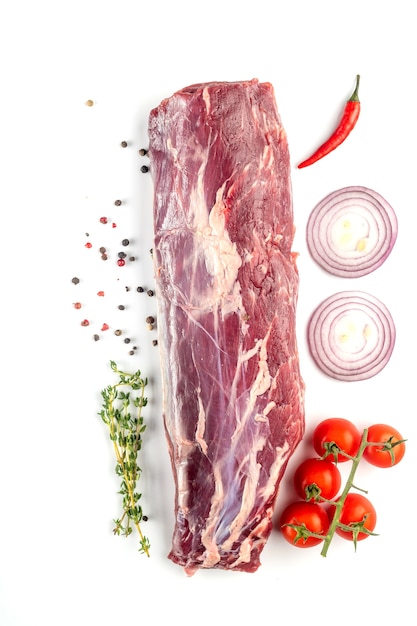 Rinderfilet. Ein großes Stück Fleisch mit Gemüse und frischen Kräutern auf weißem Hintergrund. Ansicht von oben.