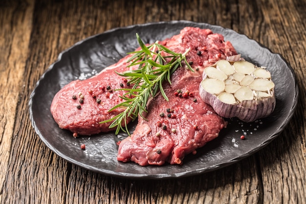 Rinderfleisch Rib-Eye Steak mit Rosmarinsalz und Pfeffer auf schwarzem Teller.