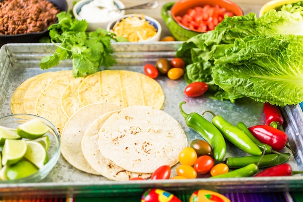 Rinderhack-Tacos mit Römersalat, Tomatenwürfeln, Radieschen und geriebenem Cheddar-Käse.