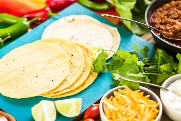 Foto rinderhack-tacos mit römersalat, tomatenwürfeln, radieschen und geriebenem cheddar-käse.