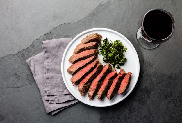 Rindersteak auf weißem Teller mit einem Glas Rotwein