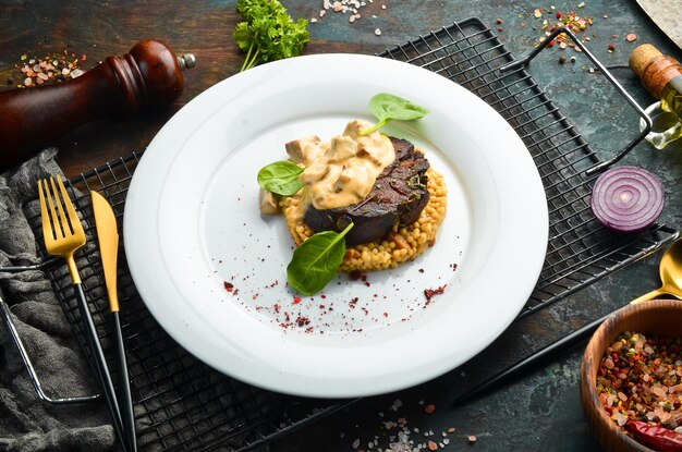 Rindersteak mit Bulgur und Pilzen auf einem Teller Speisekarte des Restaurants Europäische Küche