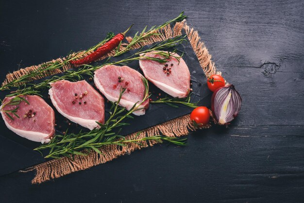 Rindersteak mit frischem Gemüse und Rosmarin und Gewürzen auf schwarzem Holzhintergrund Draufsicht Freier Platz für Text