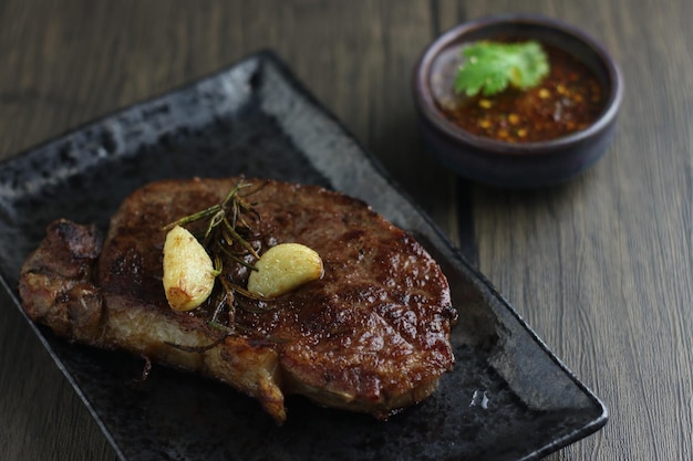 Rindersteak mit Knoblauch in schwarzer Platte auf Holztisch