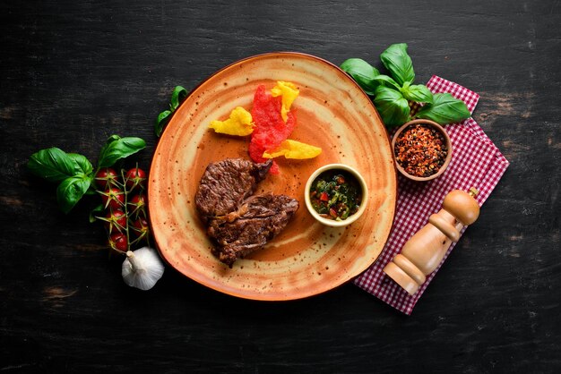 Rindersteak mit Soße auf einem Teller auf schwarzem Holzhintergrund Draufsicht Freier Kopierplatz