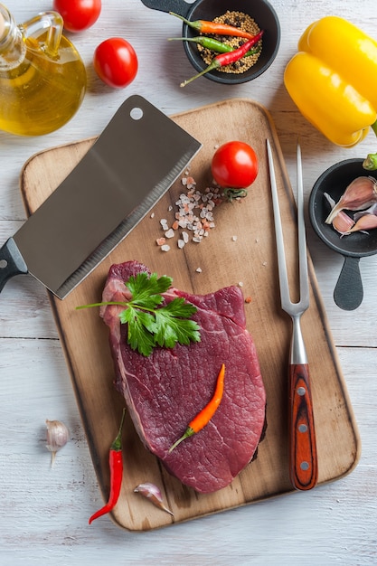 Rindersteaks kochfertig, kulinarischer Hintergrund. Frisches rohes Fleisch auf Holzschneidebrett, flach gelegt