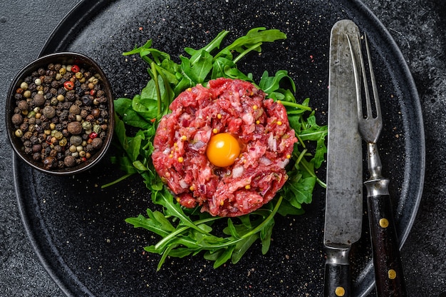 Rindertartar mit einem Wachtelei, serviert auf einer schwarzen Steinplatte.