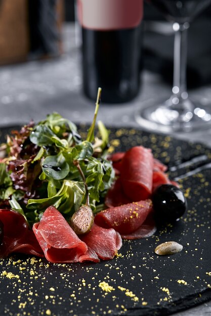 Rindfleisch-Carpaccio mit Rucola auf einem schwarzen Teller, traditionelle italienische Küche