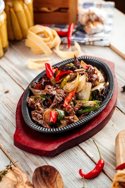 Rindfleisch in gusseisernem Pfannengemüse auf Holztisch