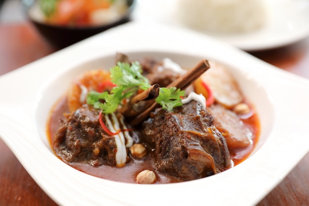 Rindfleisch-Massaman-Curry mit Reis und Salat auf hölzernem Hintergrund, thailändisches Essen