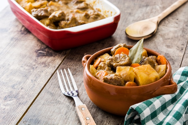 Rindfleisch mit Kartoffeln, Karotten und Gewürzen in Schüssel auf Holztisch gedünstet