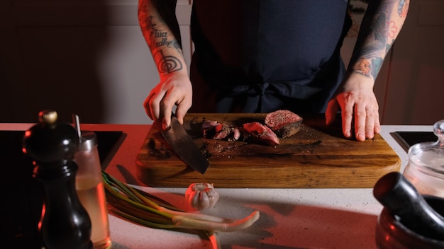 Foto rindfleisch von einem koch auf einem holztisch schneiden