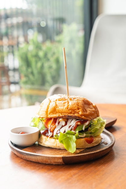 Rindfleischburger mit Käse und Sauce auf Holzteller