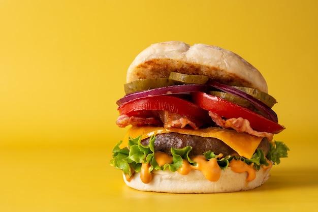 Rindfleischburger mit Käse und Speck auf gelbem Hintergrund