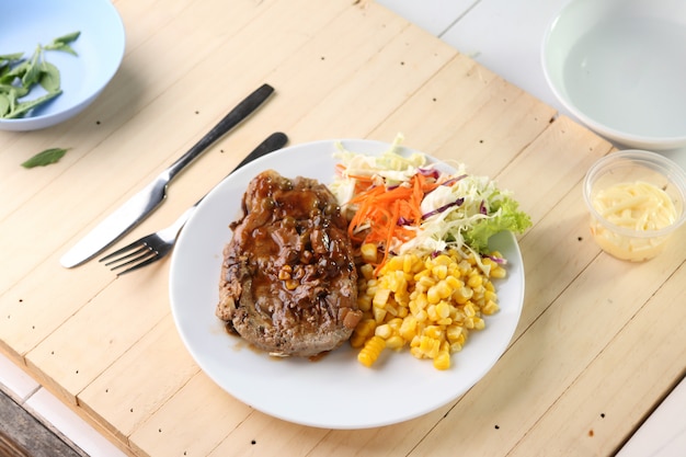 Rindfleischsteak auf weißem Teller, Plankenholz.