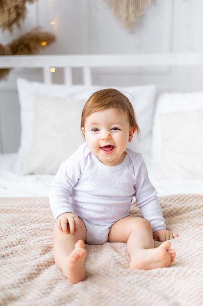 Rindo alegre garotinha na cama em um quarto brilhante sorrindo retrato fechado