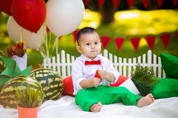 Rindo bebê 1-2 anos de idade comendo melancia ao ar livre. Conceito de festa de verão