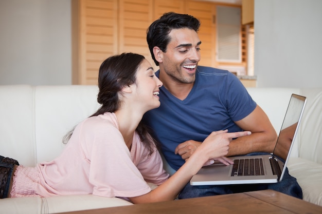 Rindo jovem casal usando um laptop