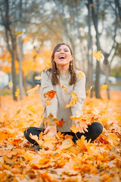 Foto rindo jovem se divertindo no outono parque brincando com folhas caídas
