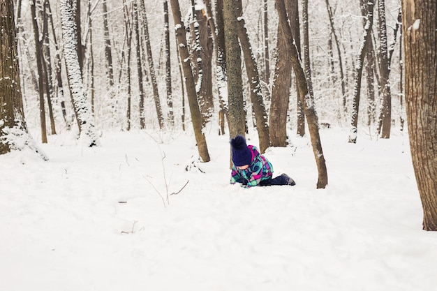 Rindo menina deitada na neve profunda.