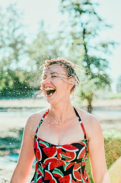 rindo mulher loira emocional com cabelo molhado fazendo salpicos de água. Férias, felicidade, diversão