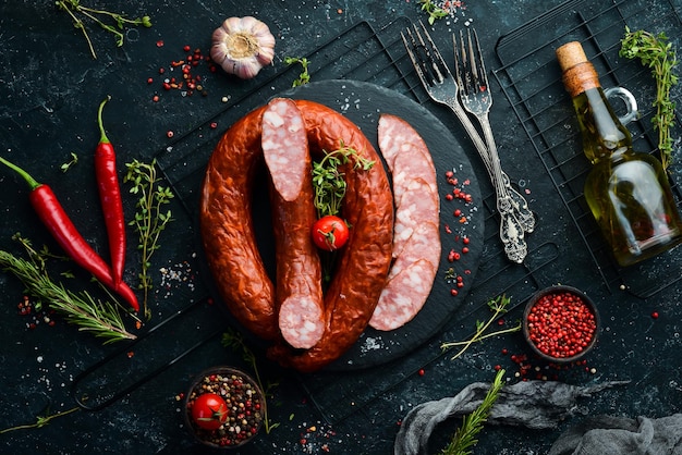 Ringe aus traditioneller Räucherwurst in einer Komposition im Landhausstil auf schwarzem Steinhintergrund Draufsicht Freier Platz für Text