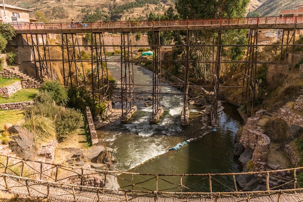 río cerca de construcción de piedra y puente de metal en checacupe, cusco, perú