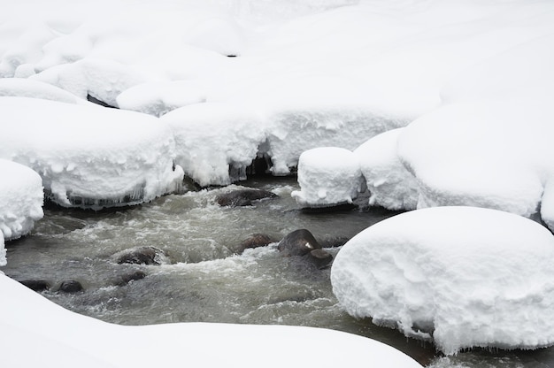 Rio de montanha após a queda de neve. Linda paisagem de inverno