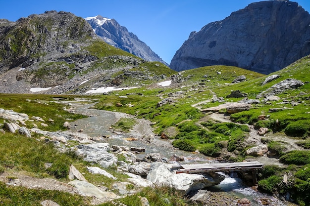 Rio de montanha e ponte de madeira no vale alpino do Parque Nacional de Vanoise, Savoie, Alpes franceses