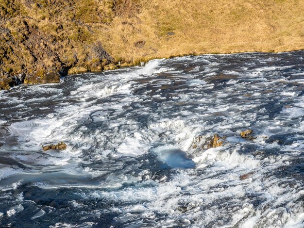 Rio fluindo no topo da cachoeira Skogafoss com neve e gelo na temporada de inverno na Islândia