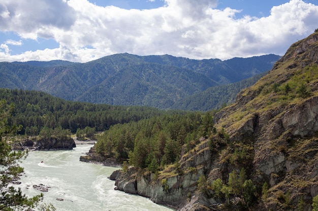 Un río de montaña ancho y caudaloso que fluye rápido. Grandes rocas sobresalen del agua.