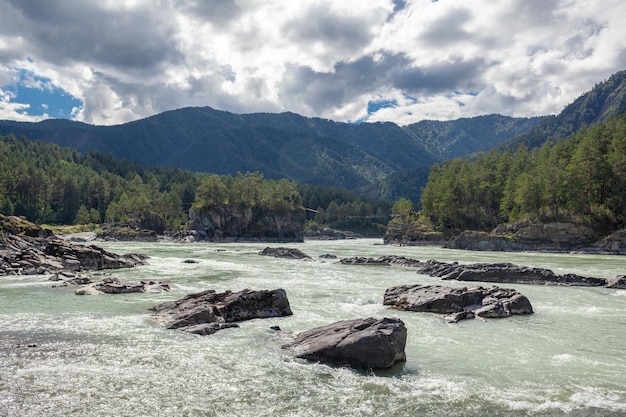 Un río de montaña ancho y caudaloso que fluye rápido. Grandes rocas sobresalen del agua.